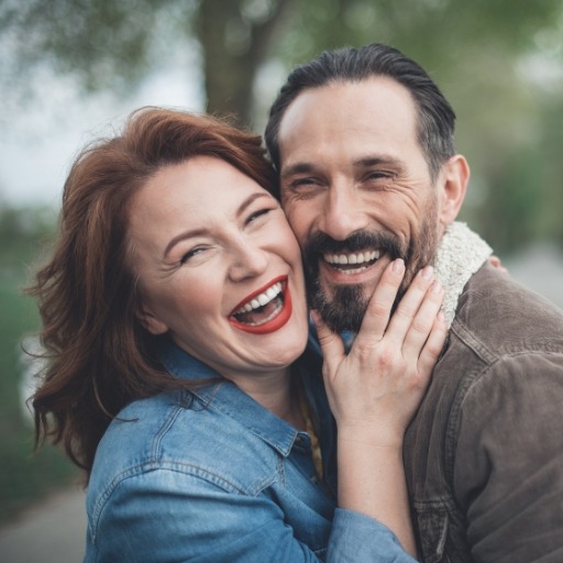 Man and woman laughing together after dental implant tooth replacement