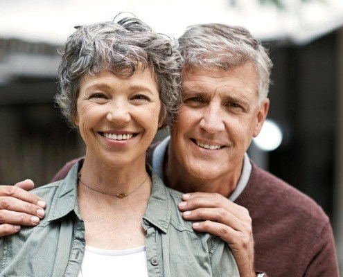 Man and woman smiling after replacing missing teeth