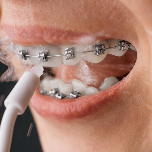 woman using water flosser traditional braces in Winfield 