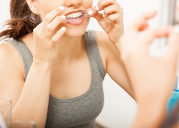 Woman putting on teeth whitening strip at home