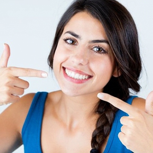 A patient pointing to her smile after cosmetic bonding in Winfield, KS