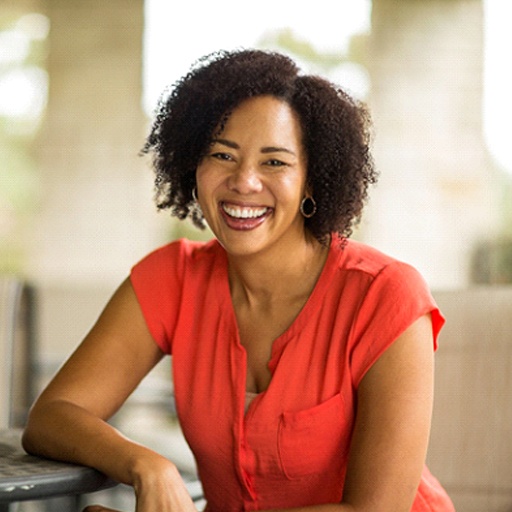 Woman in orange shirt smiling while sitting outside