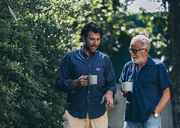 Two men holding cups talking outisde
