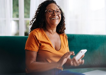 Smiling woman looking at her phone on couch