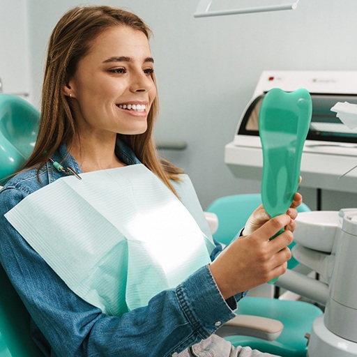 Female patient checking her smile in a handheld mirror