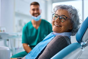 Woman with black glasses smiling in treatment chair