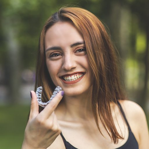 Smiling woman holding an Invisalign tray