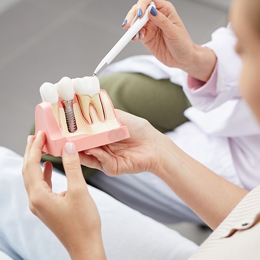 Dentist and patient looking at denal implant tooth replacement model