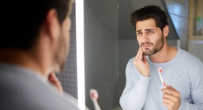 Man in need of emergency dentistry holding cheek in pain