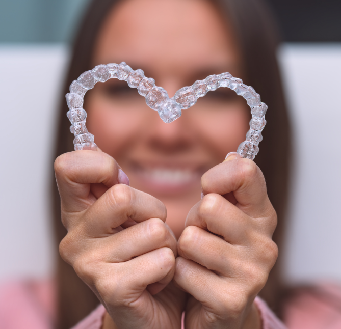 Woman holding clear aligners in heart shape