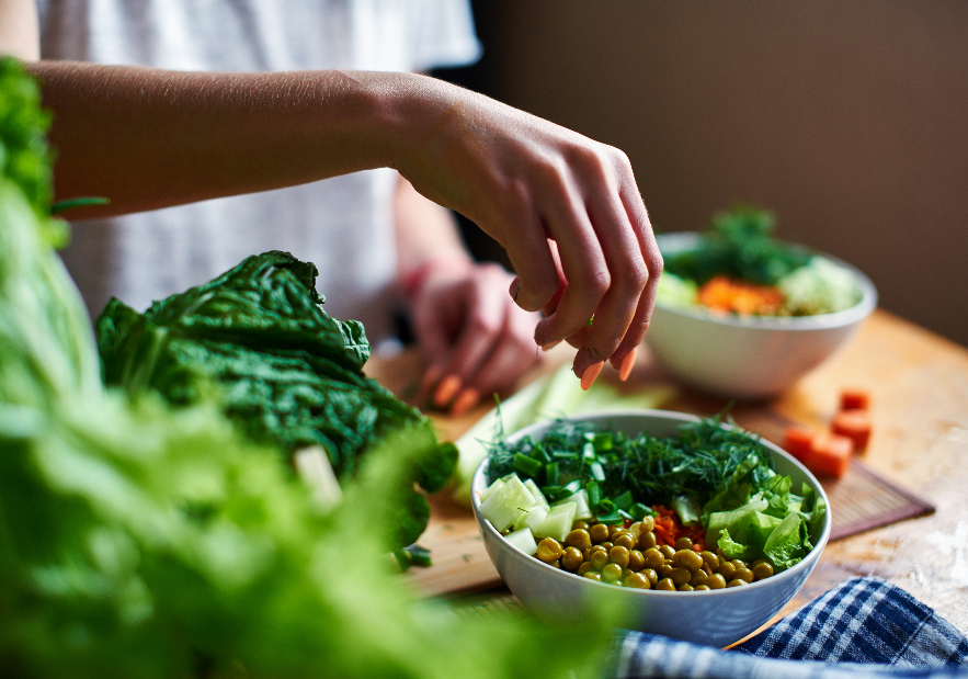 Close up of woman's hands making salad bowl